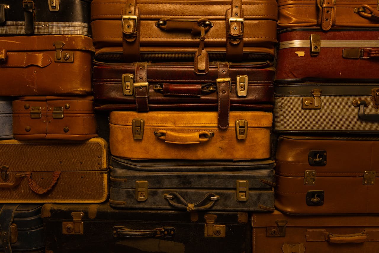 A collection of vintage suitcases stacked together, showcasing a variety of textures and colors.